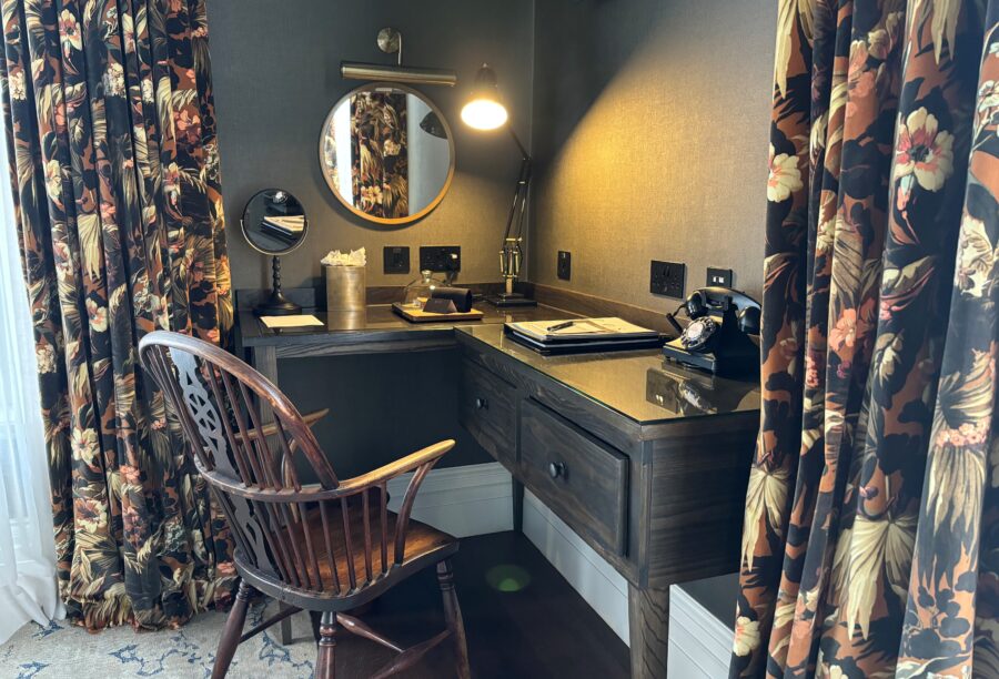 A view of a corner desk with a desk lamp, telephone, mirror, and chair at Manor House Lindley.