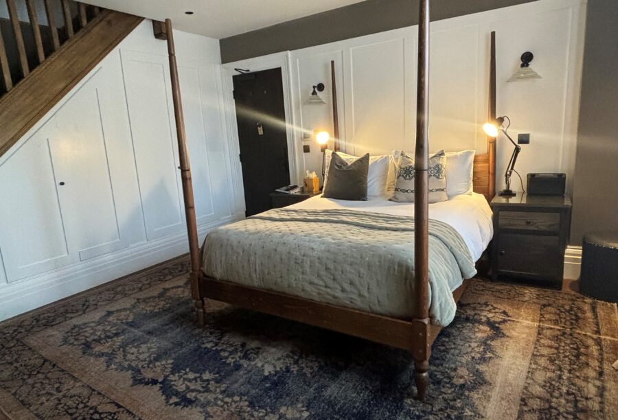 A closer view of a four-poster bed at Manor House Lindley against wooden paneling.