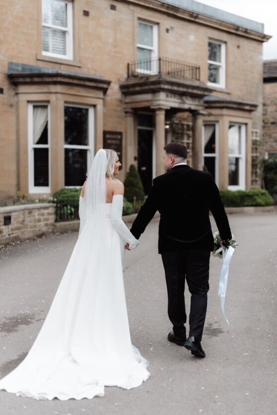 A wedding at Manor House Lindley with the bride and groom walking towards the entrance.