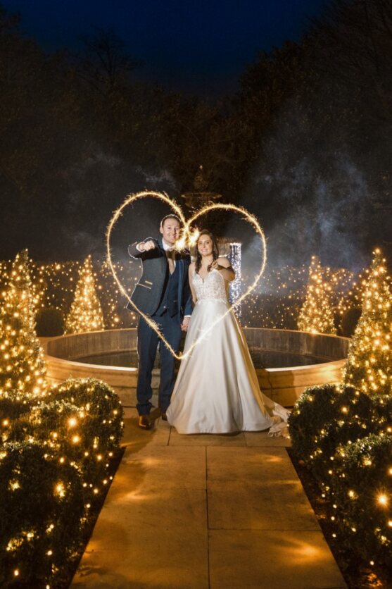 Bride and groom making a heart shape with a sparkler in the dark