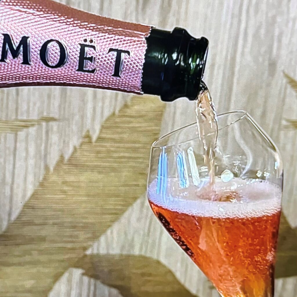 A close-up of Rosé Moët being poured into a champagne glass