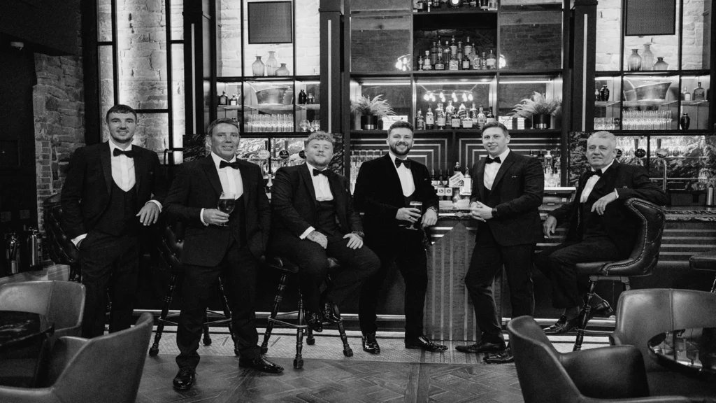 Black and white picture of groom, best man, friends and family at the bar at Manor House