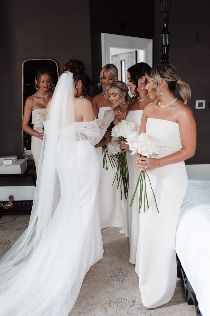 Bride and bridesmaid in the room at getting ready together inside at Manor House bedroom