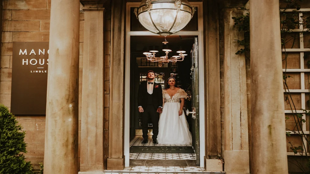 Bride, Grace and Groom Rob at the entrance of the Manor House Lindley