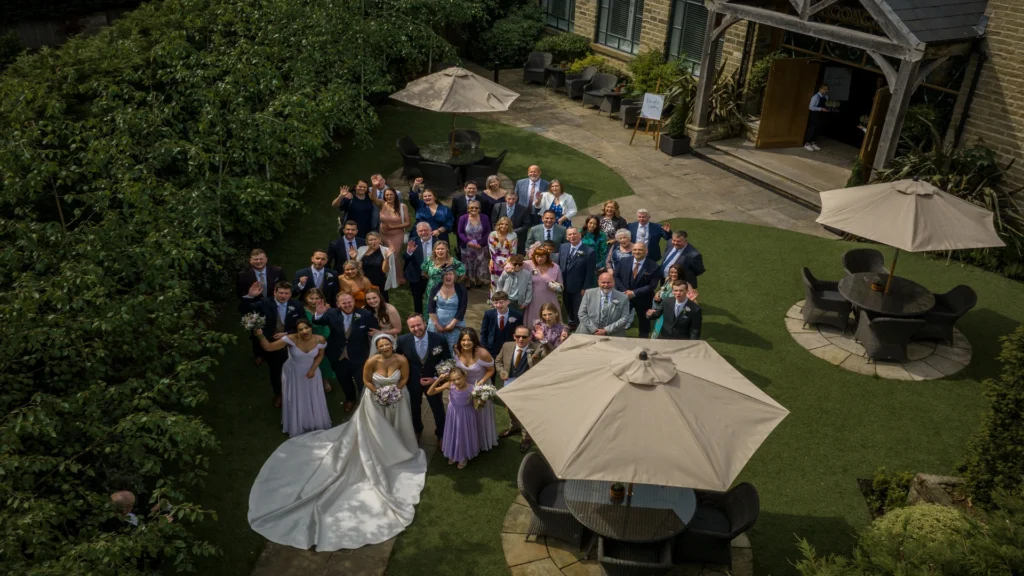 An aerial picture of bride, groom, family and friends in the grounds at Manor House Lindley