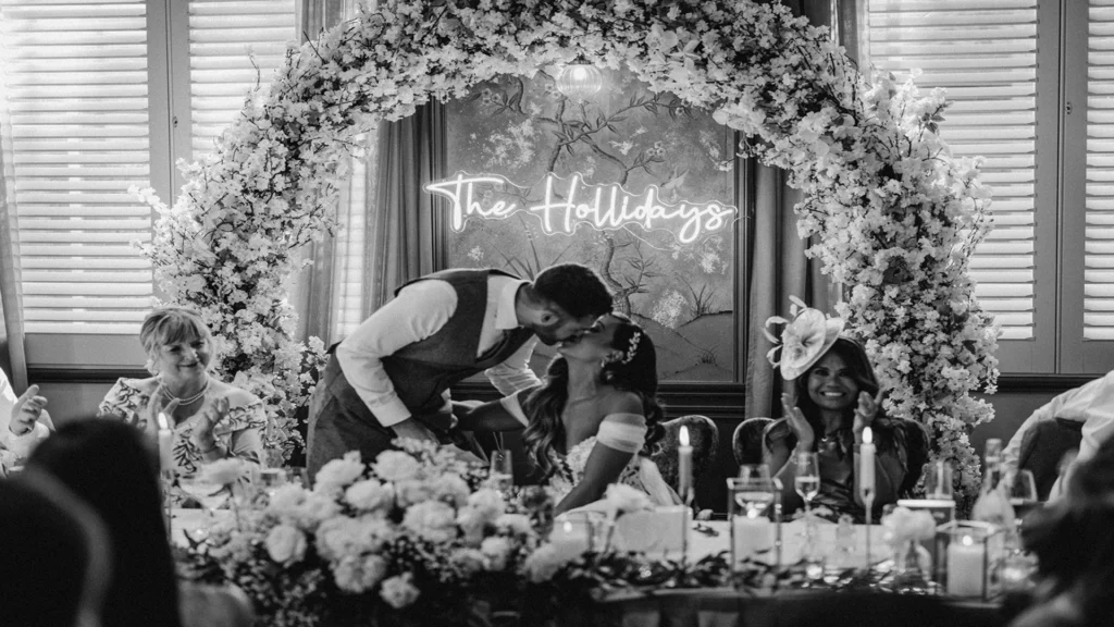 Black and white image of bride and groom kissing on the top table