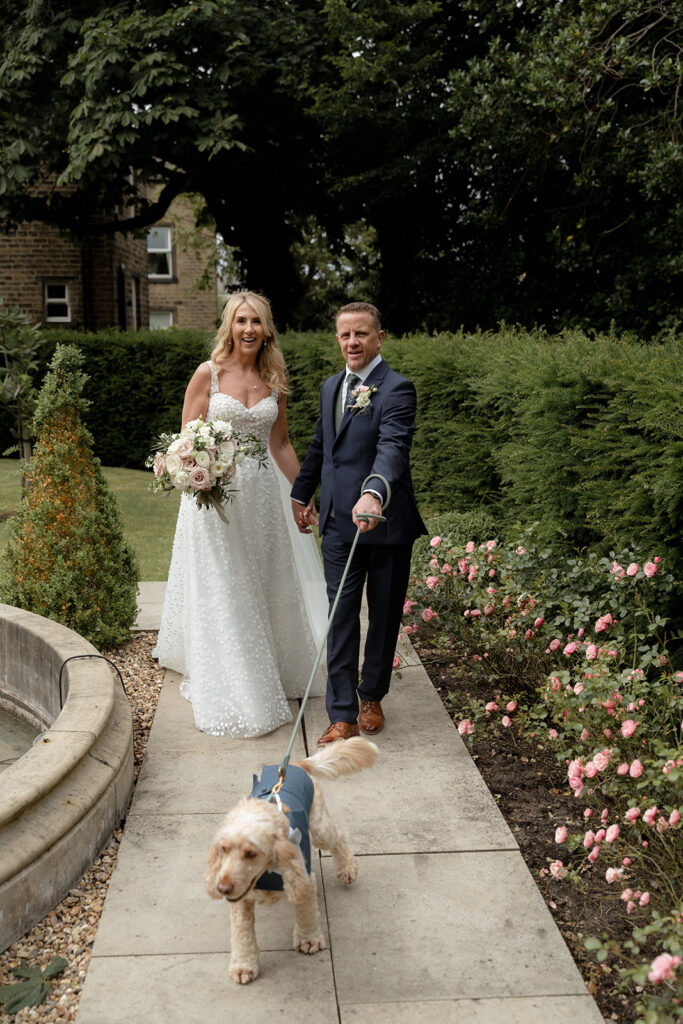 Groom Aaron and Bride Sam walking the dog outside Manor House Lindley