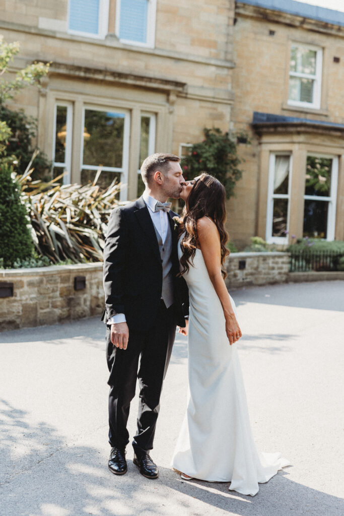 Bride Alanna & Tom Groom kissing outside Manor House Lindley