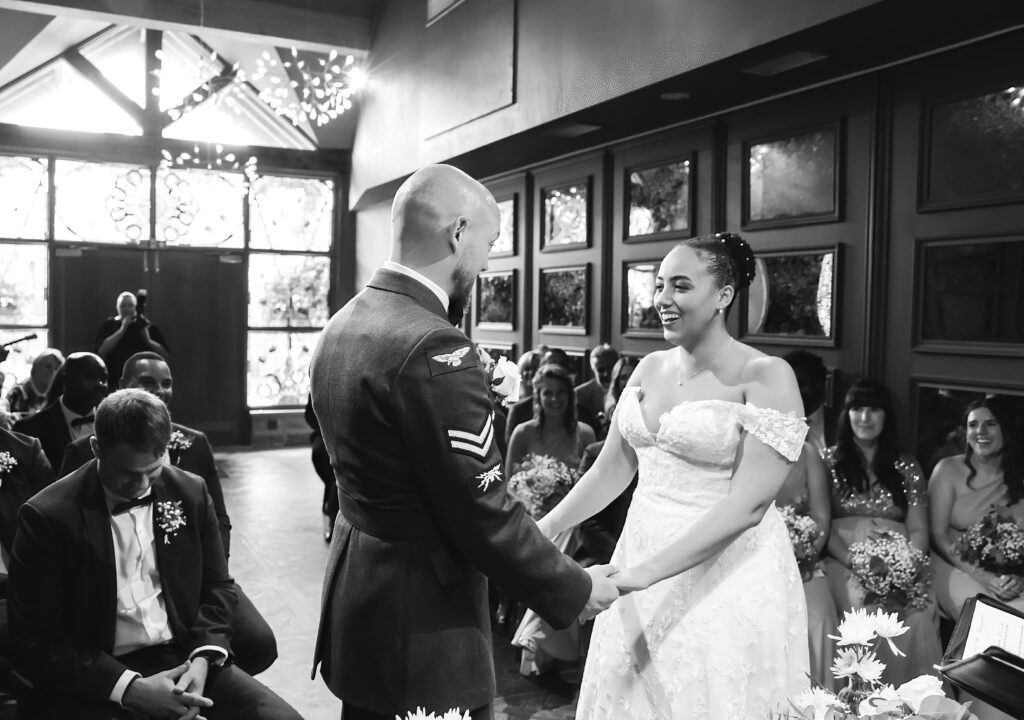 Black and white picture of the bride and groom in the aisle inside the wedding venue at Manor House Lindley.