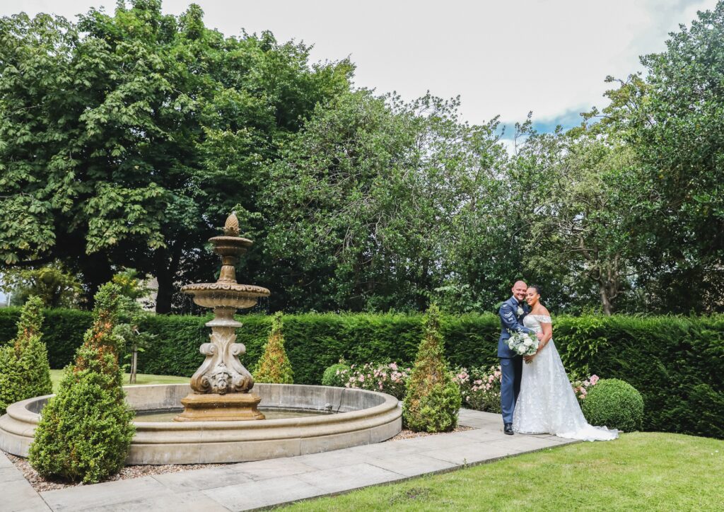 Bride and Groom next to the fountain outside at Manor House Lindley