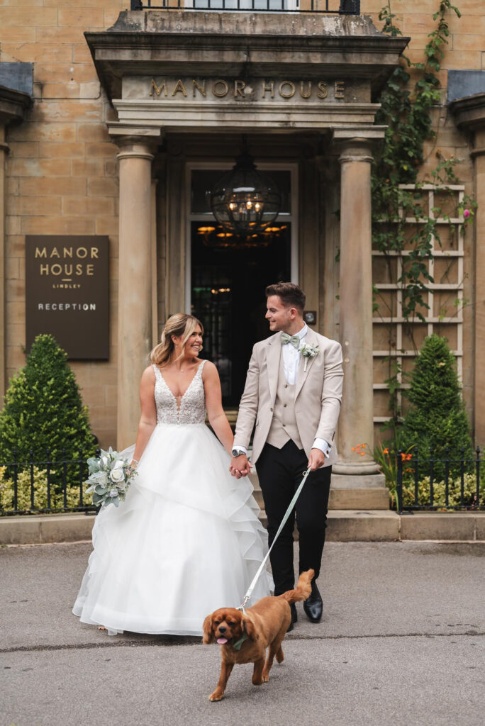 Picture of bride and groom outside the entrance of Manor House Lindley with dog