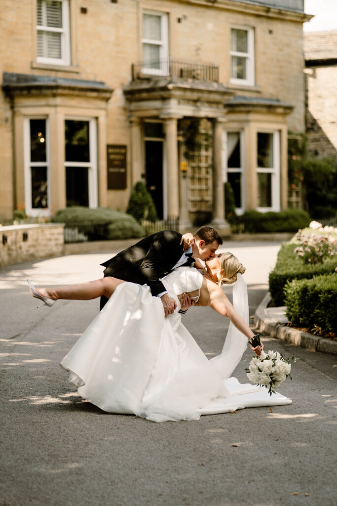 Bride Cara and Groom Shaun kissing outside the ground at Manor House Lindley