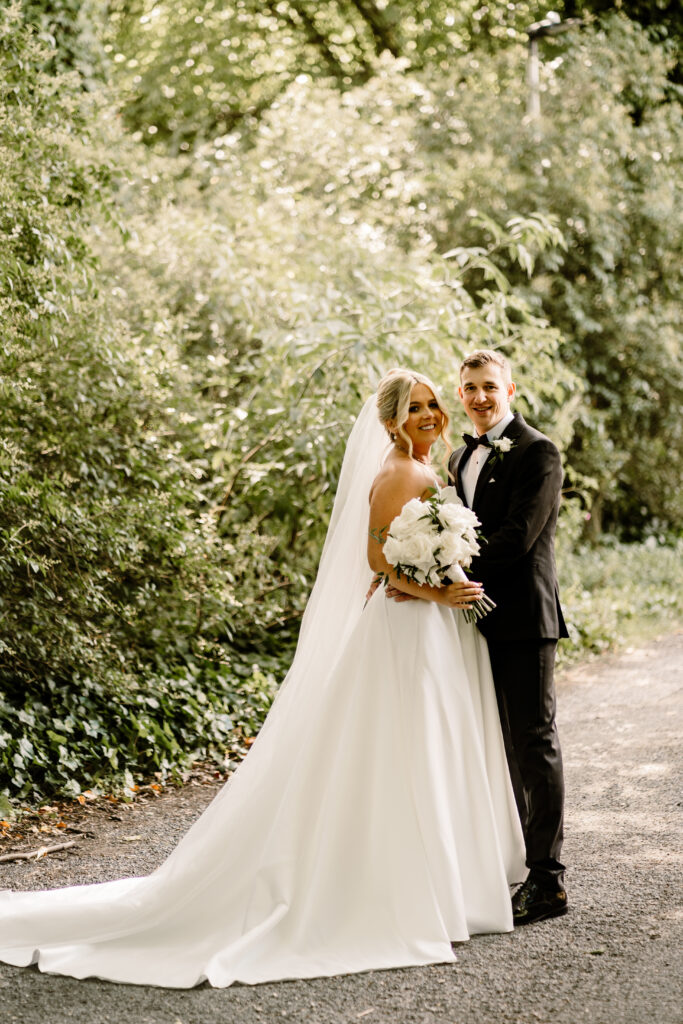 Bride Cara with white flowers and Groom Shaun outside the ground at Manor House Lindley