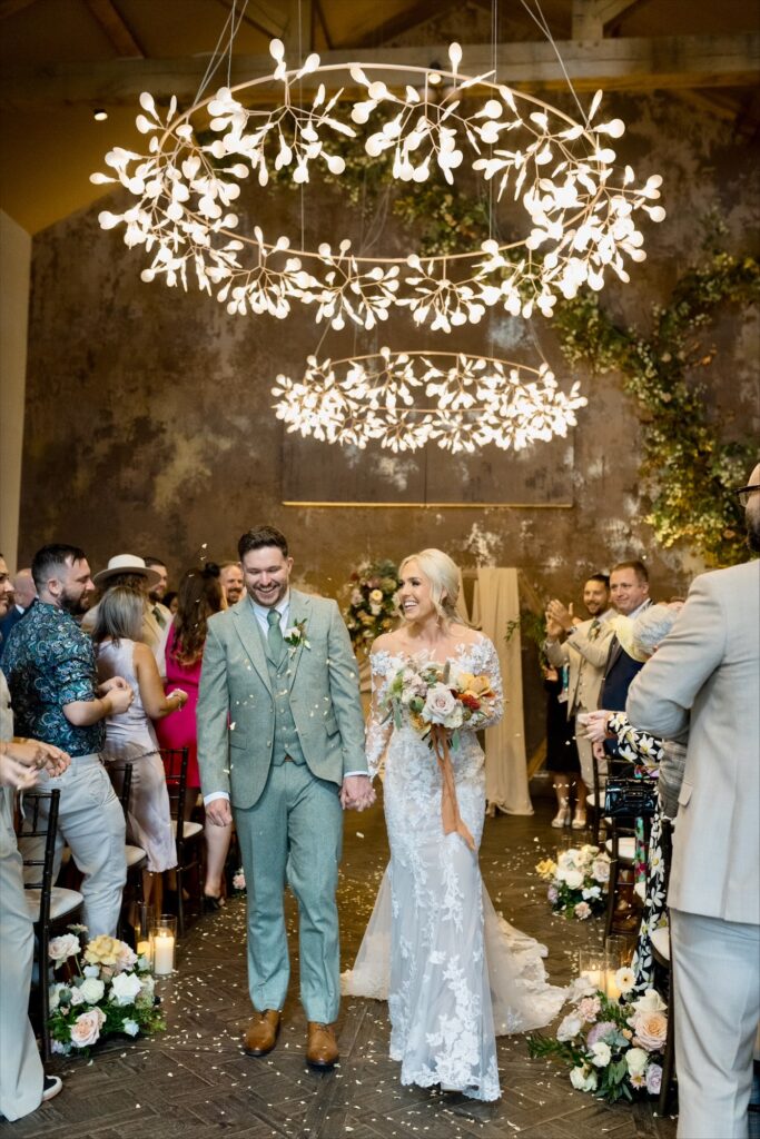 Bride and groom walking down the aisle after getting married inside the wedding venue at Manor House.